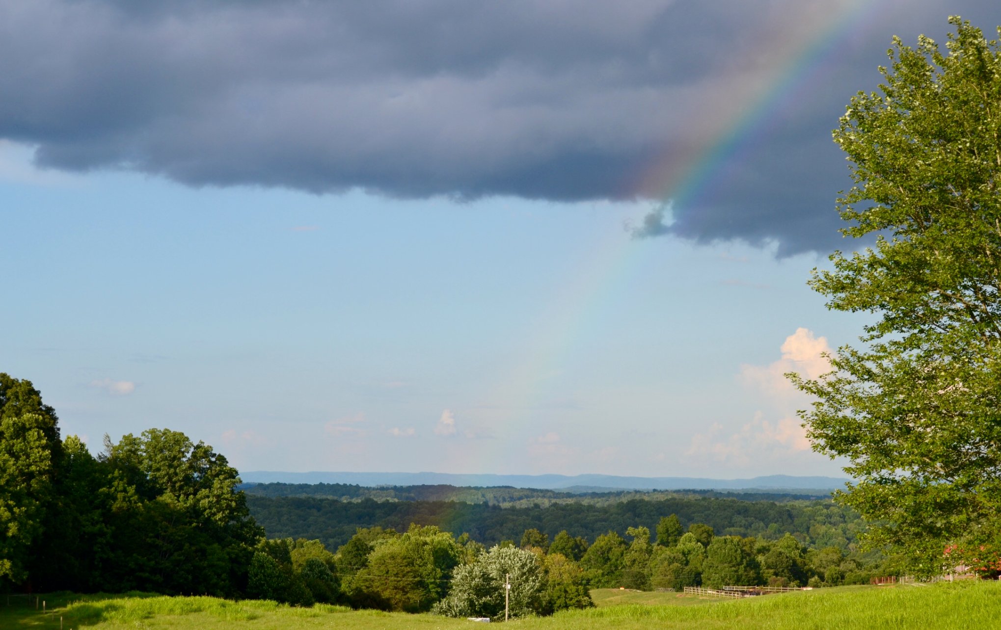 Rainbow arching over green pasture and valley views