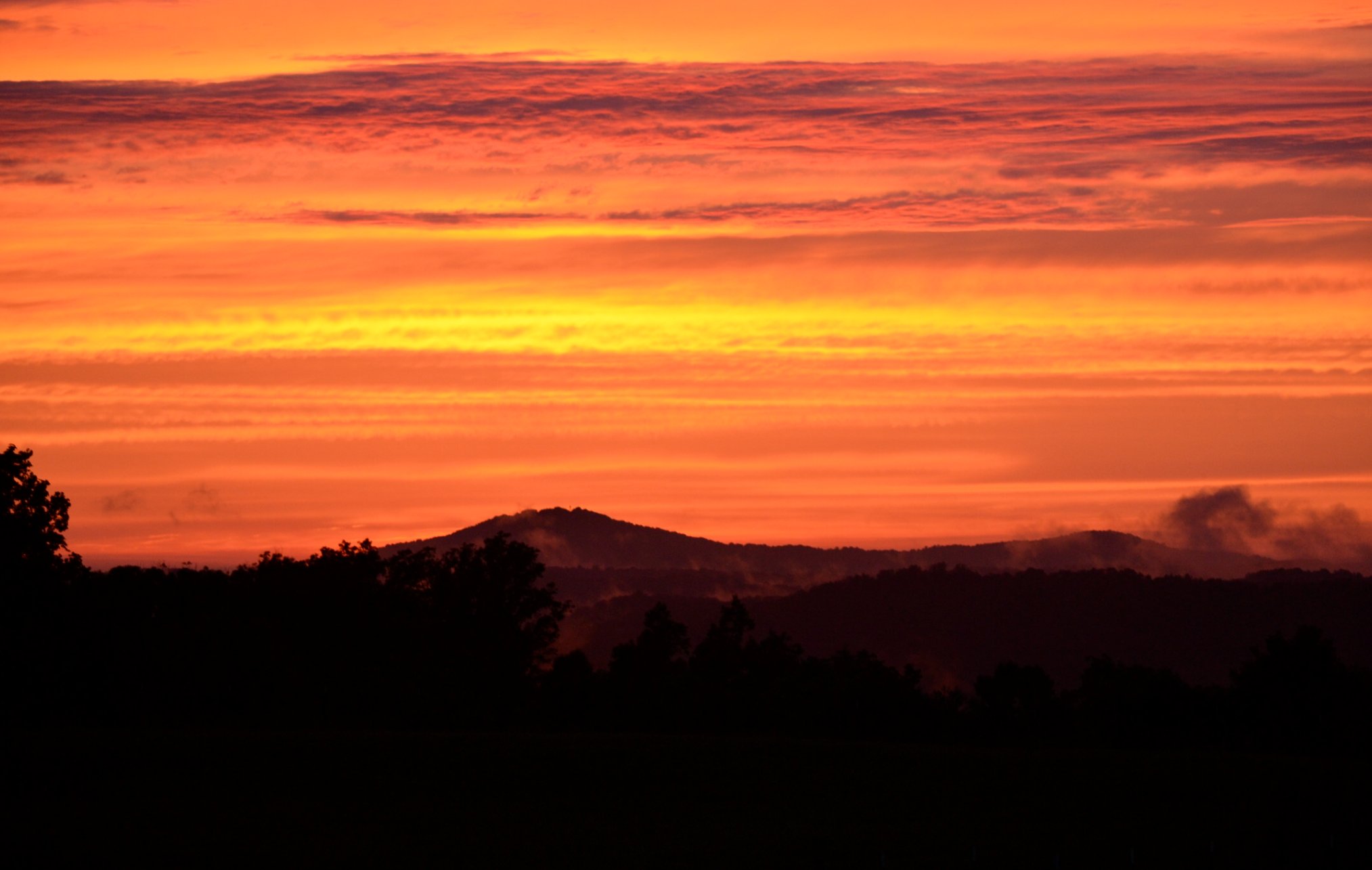 Layered orange and red sunset over silhouetted ridgeline